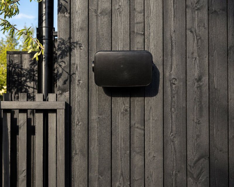 Sonance utomhushögtalare monterad på svart träfasad